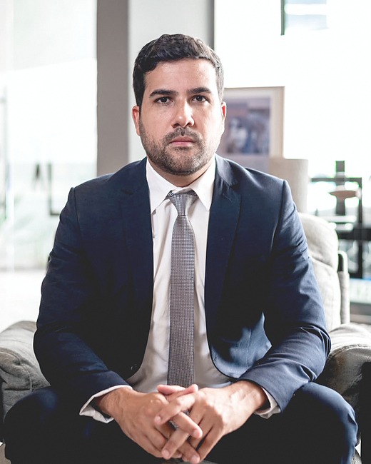 Renan Alonso Barreto, advogado, sentado no escritório, em retrato em preto e branco.